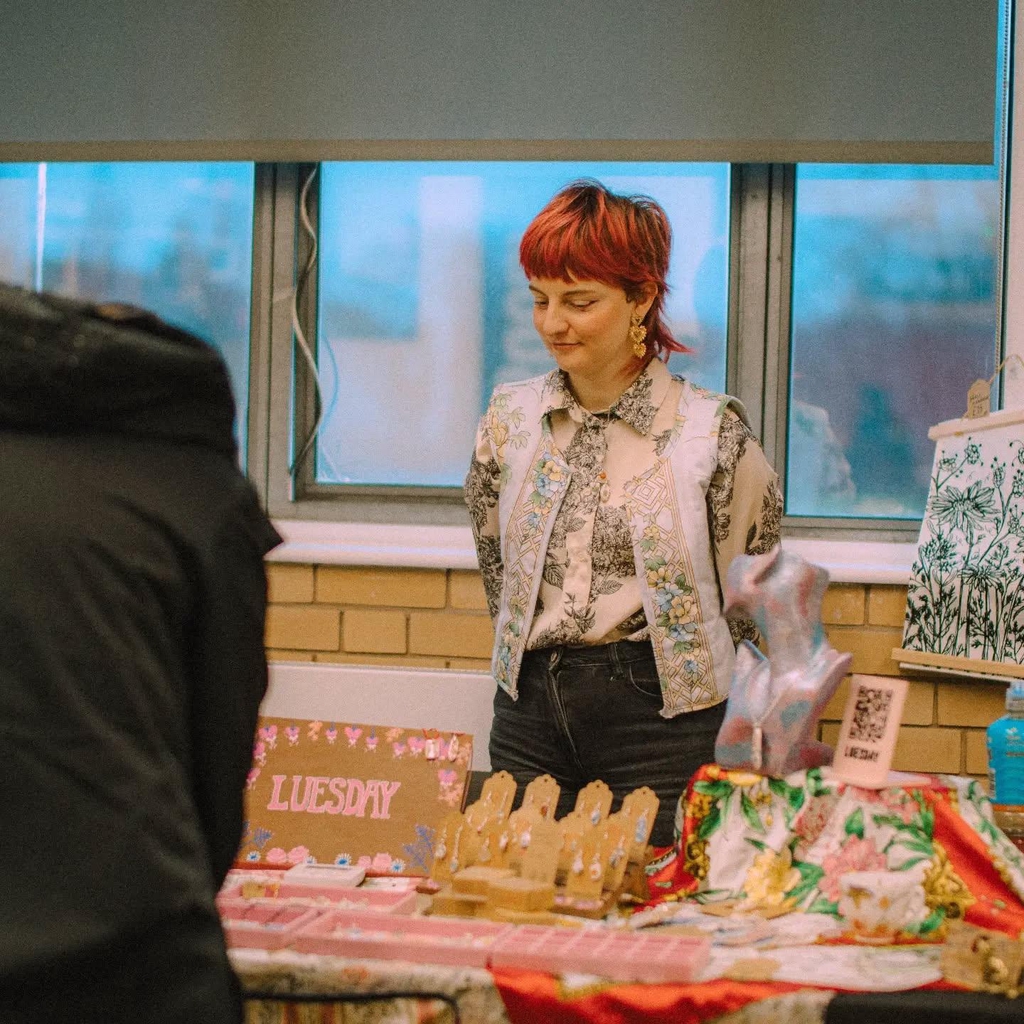 Luesday artist Lucy Kelly stood behind her colourful market stall. 