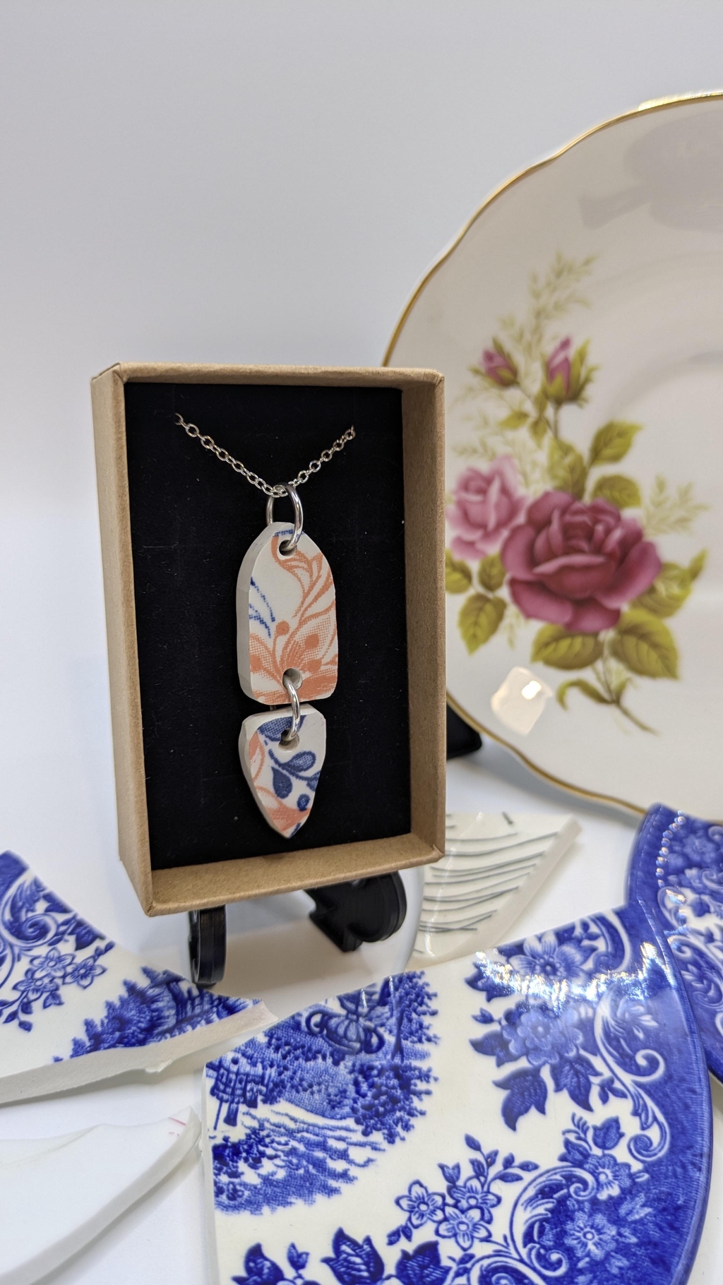 A handmade pendant made from vintage plates that is in a gift box 