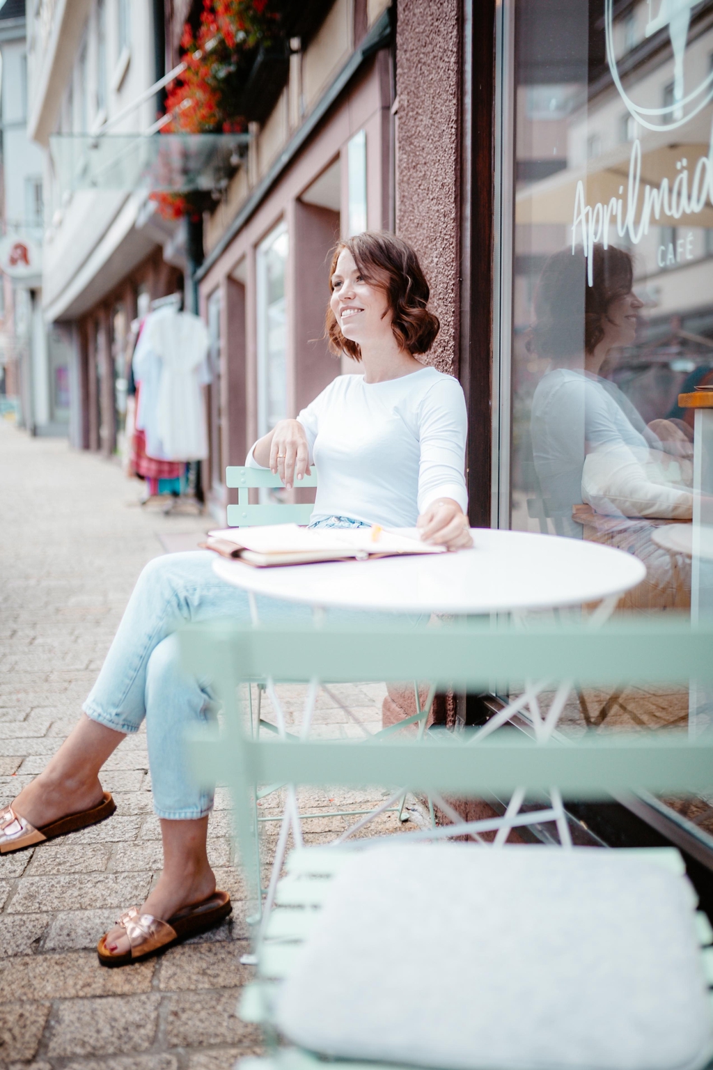 Autorin Lena Österle sitzt draußen im Café und genießt das Wetter und lässt sich inspirieren. 